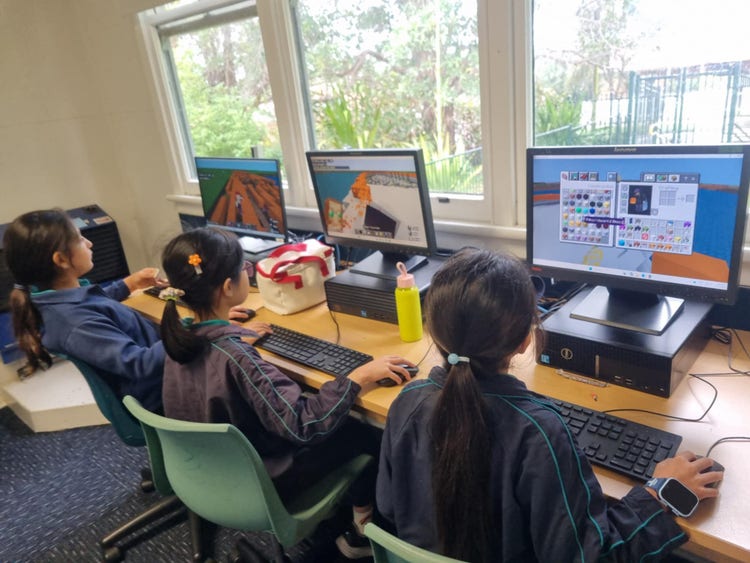 3 students working on desktop computers
