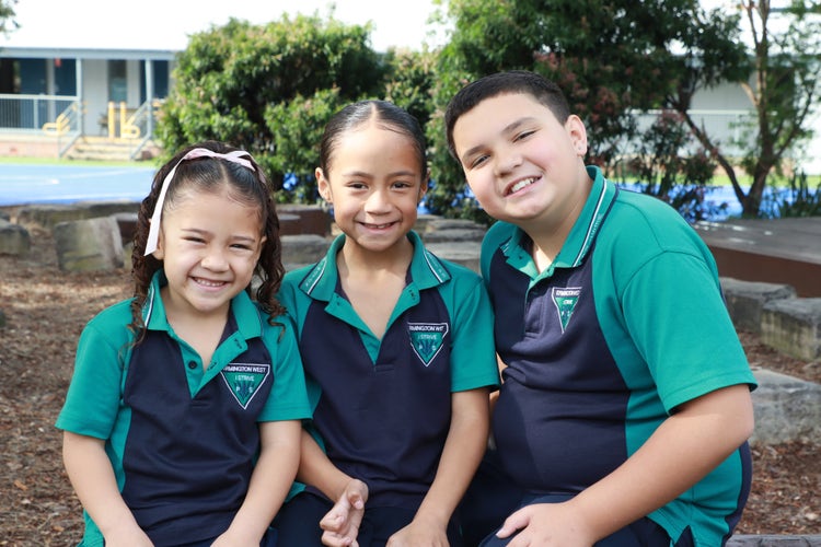 3 children from the same family smiling at the camera